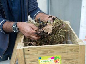 Photo montrant une personne qui fait du compostage avec des feuilles, de l'herbe... 
